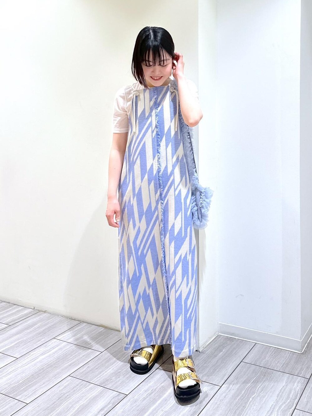 ゴールド系のサンダル、ホワイト系のTシャツ/カットソー、ブルー系のショルダーバッグを着用したレディースの春コーディネートの1枚目の写真