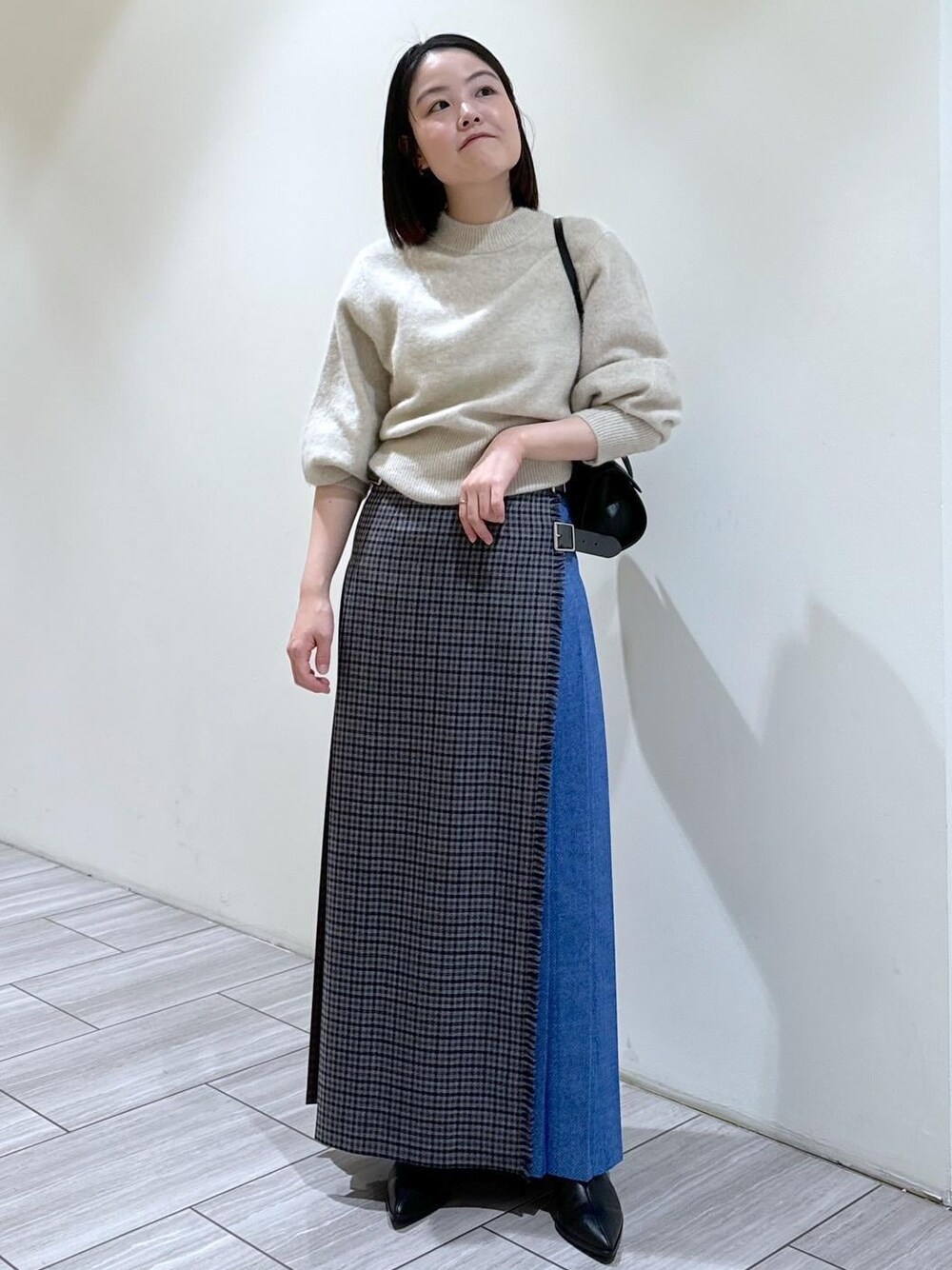 ブラック系のブーツ、ブラック系のショルダーバッグ、ホワイト系のニット/セーターを着用したレディースの秋コーディネートの1枚目の写真