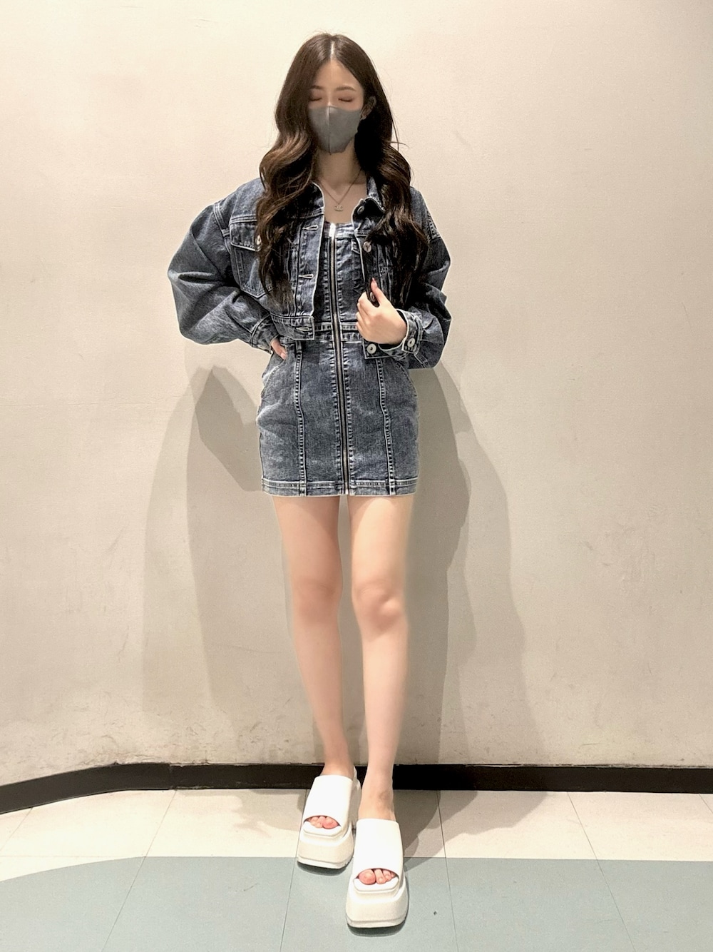 ブルー系のデニムジャケット、ブルー系のワンピース、ホワイト系のサンダルを着用したレディースの春コーディネートの1枚目の写真
