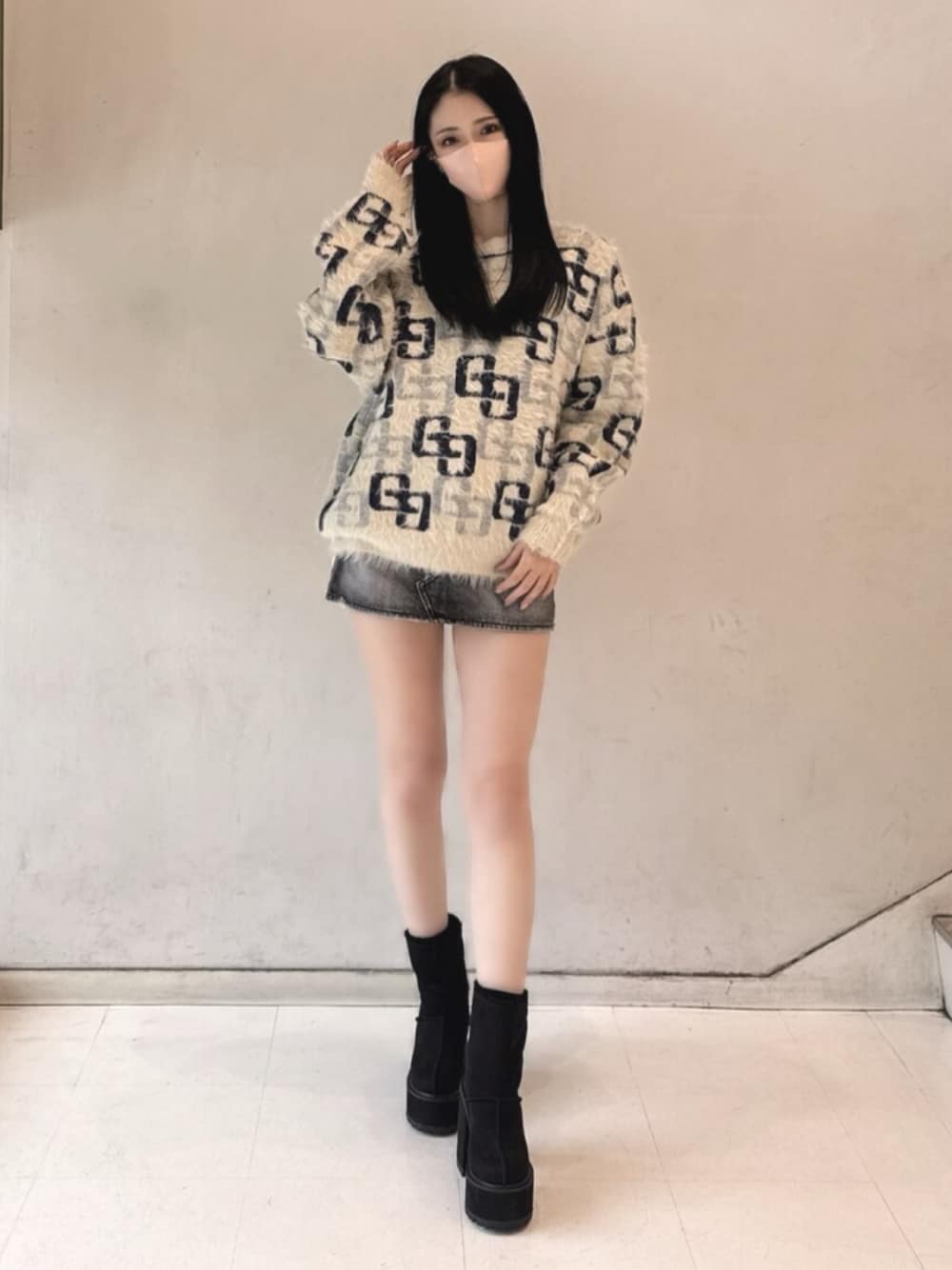 ブラック系のデニムスカート、ホワイト系のニット/セーター、ブラック系のブーツを着用したレディースの冬コーディネートの1枚目の写真