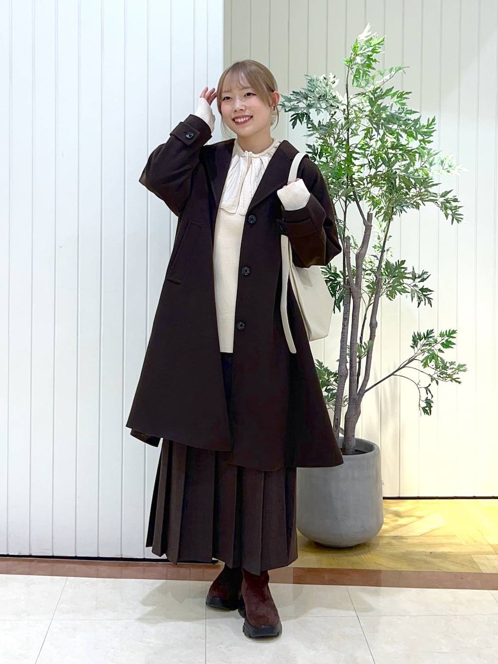 ブラウン系のショルダーバッグ、ブラウン系のブーツ、ブラウン系のスカートを着用したレディースの秋コーディネートの1枚目の写真