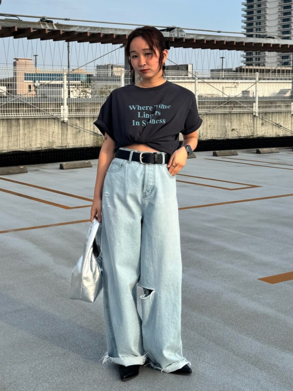 グレー系のTシャツ/カットソー、ブルー系のデニムパンツ、シルバー系のハンドバッグを着用したレディースの春コーディネートの1枚目の写真