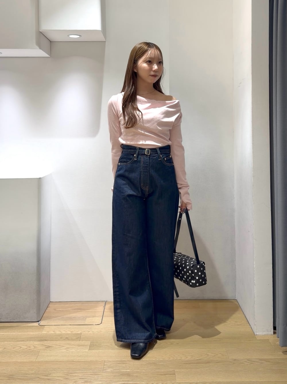 ピンク系のニット/セーター、ブルー系のデニムパンツ、ブラック系のブーツを着用したレディースの秋コーディネートの1枚目の写真