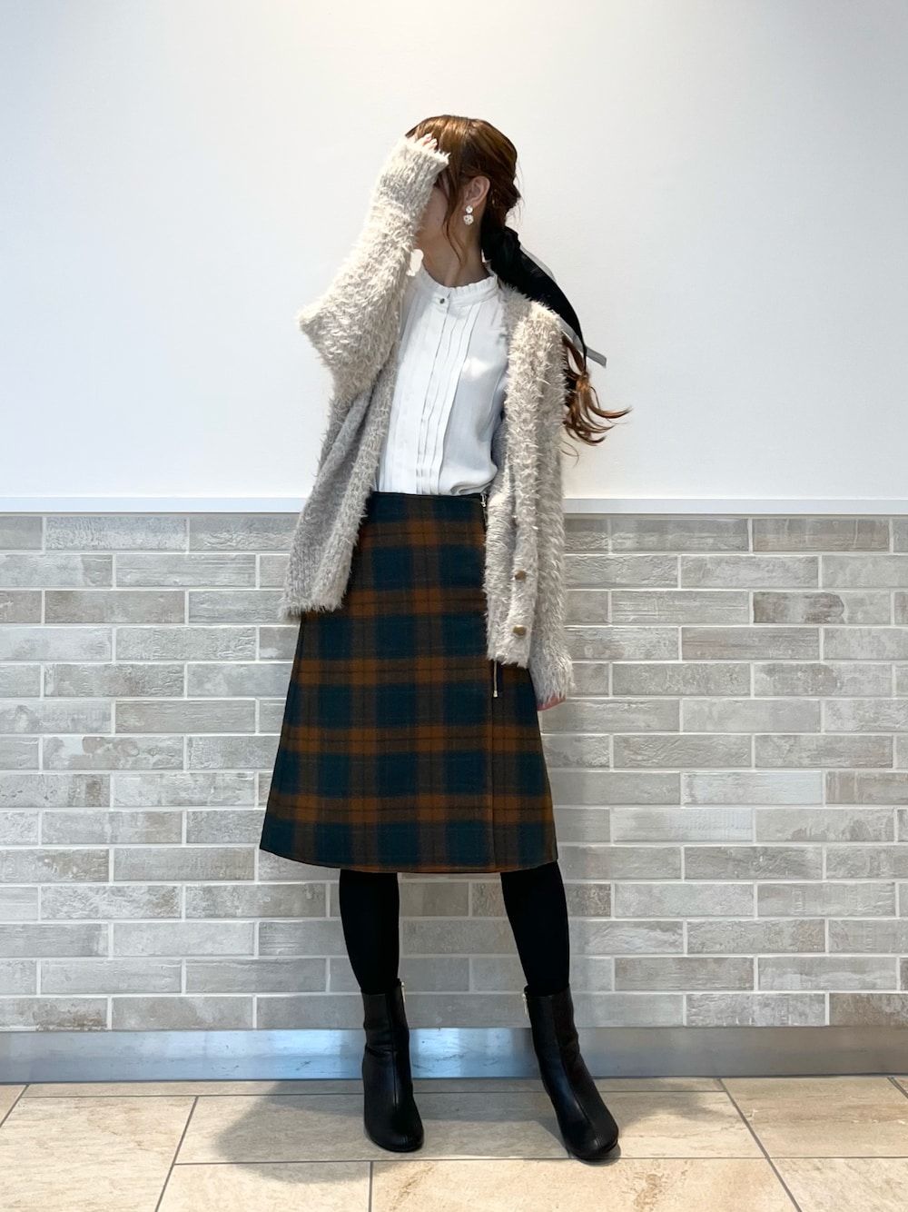 オレンジ系のスカート、ホワイト系のシャツ/ブラウス、ベージュ系のニット/セーターを着用したレディースの秋コーディネートの1枚目の写真