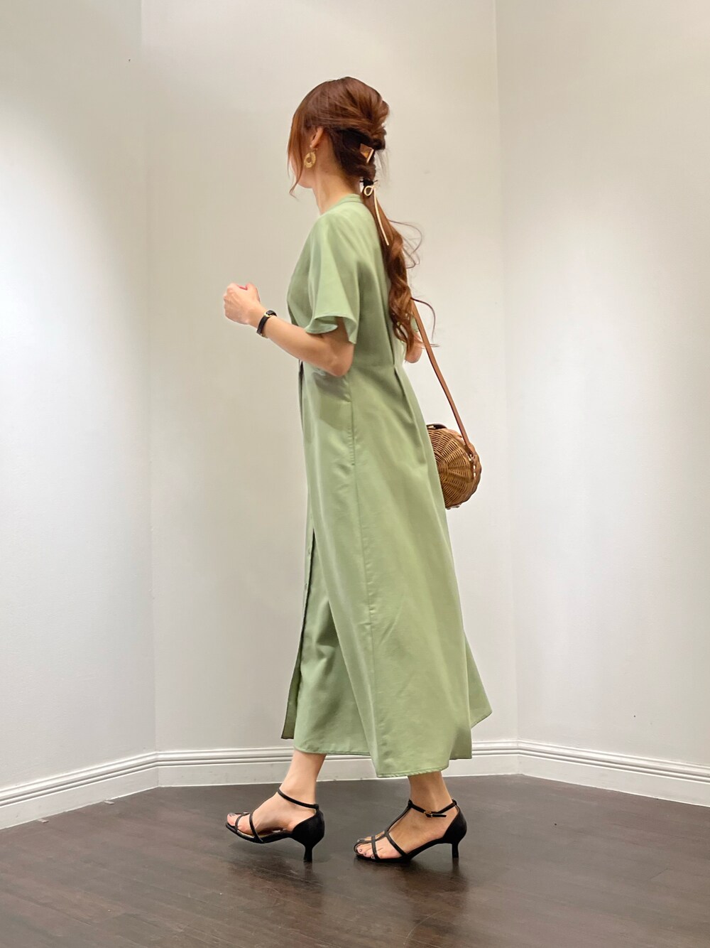 グリーン系のワンピース、ブラック系のサンダル、ブラウン系のバッグを着用したレディースの春コーディネートの1枚目の写真
