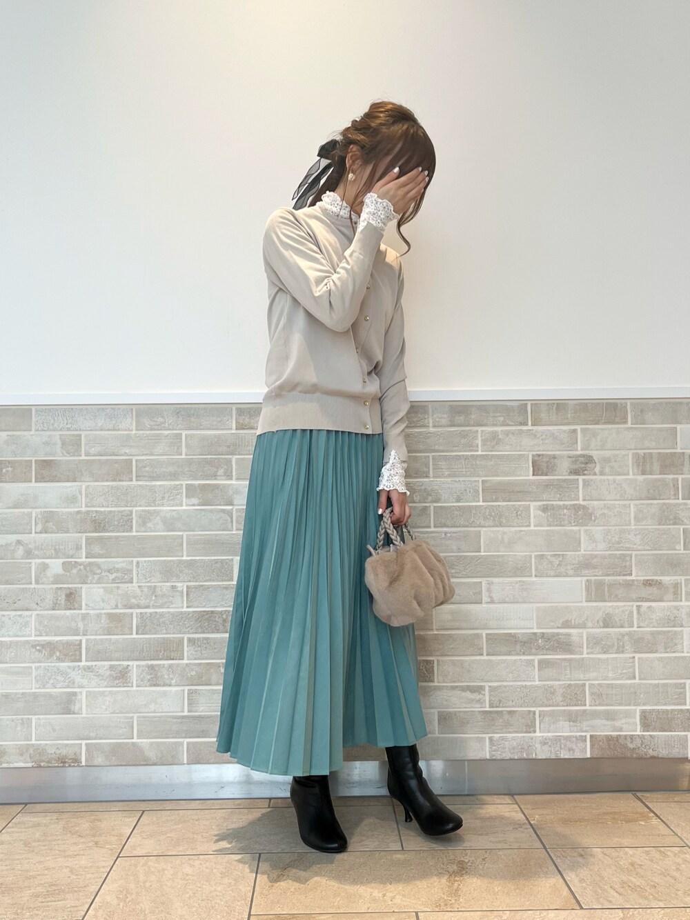 ブラック系のブーツ、グリーン系のスカート、ベージュ系のハンドバッグを着用したレディースの秋コーディネートの1枚目の写真