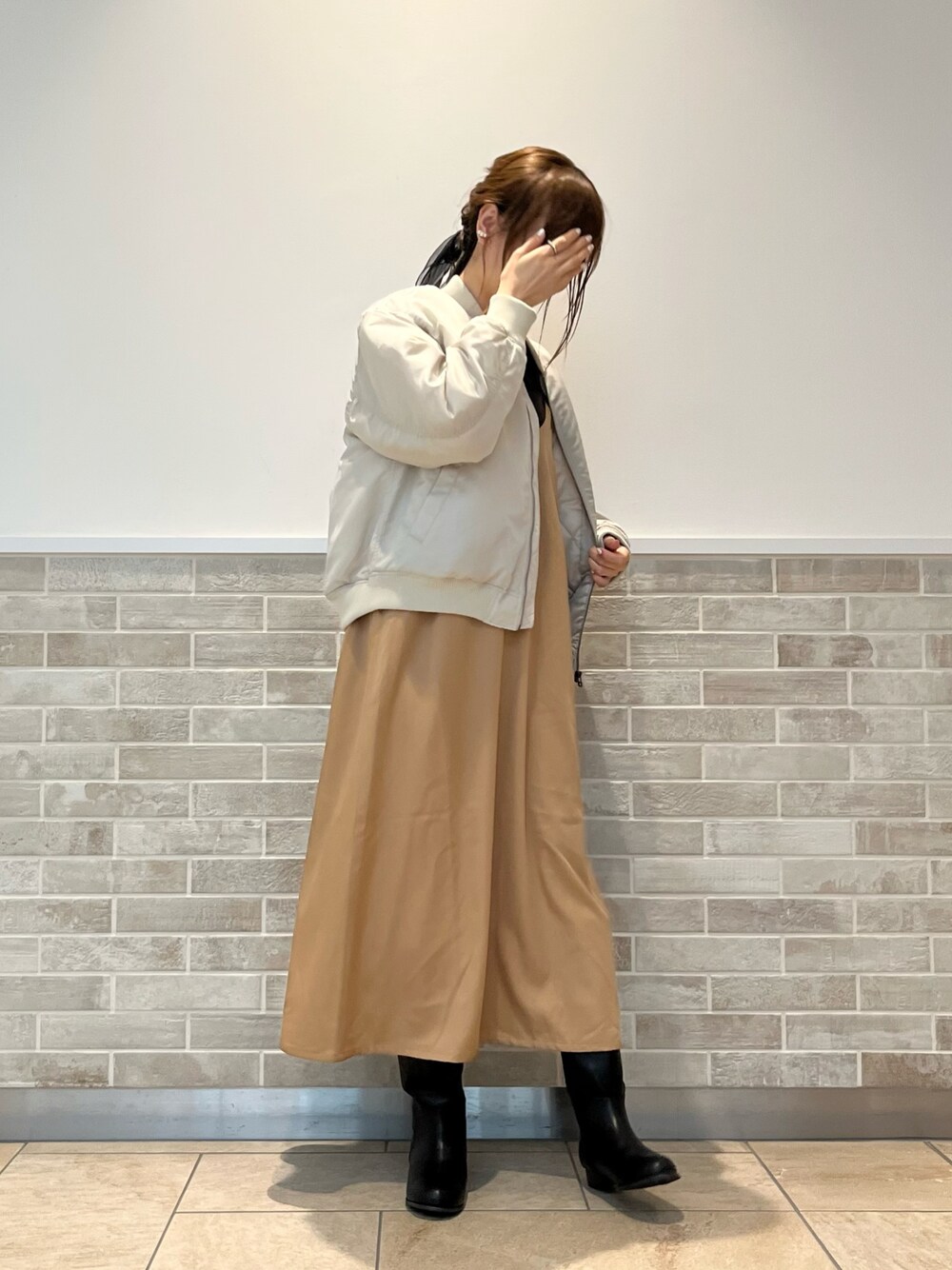 ベージュ系のブルゾン、ベージュ系のワンピース、ブラック系のブーツを着用したレディースの秋コーディネートの1枚目の写真