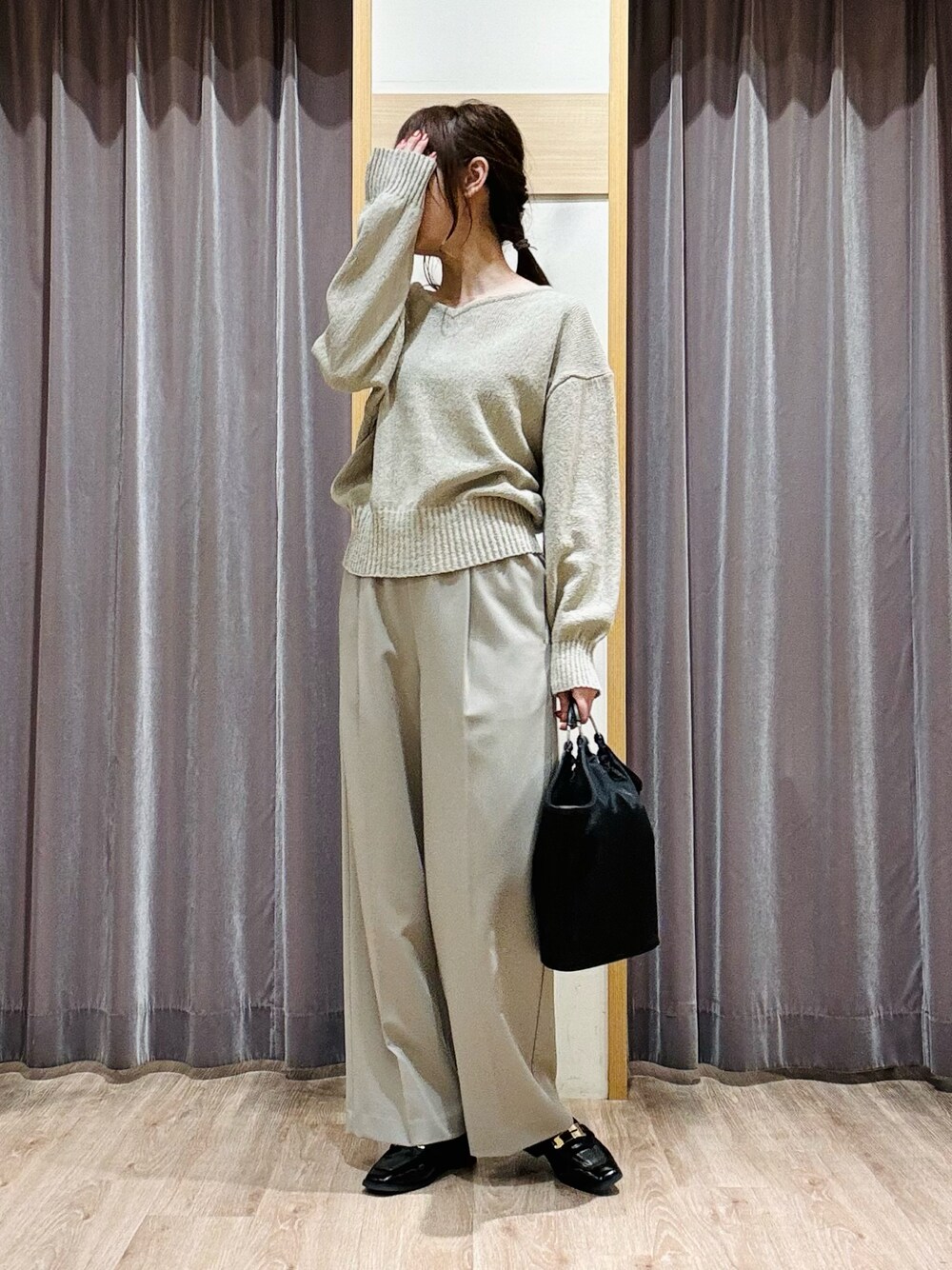 グリーン系のニット/セーター、ベージュ系のその他パンツ、ブラック系のハンドバッグを着用したレディースの春コーディネートの1枚目の写真