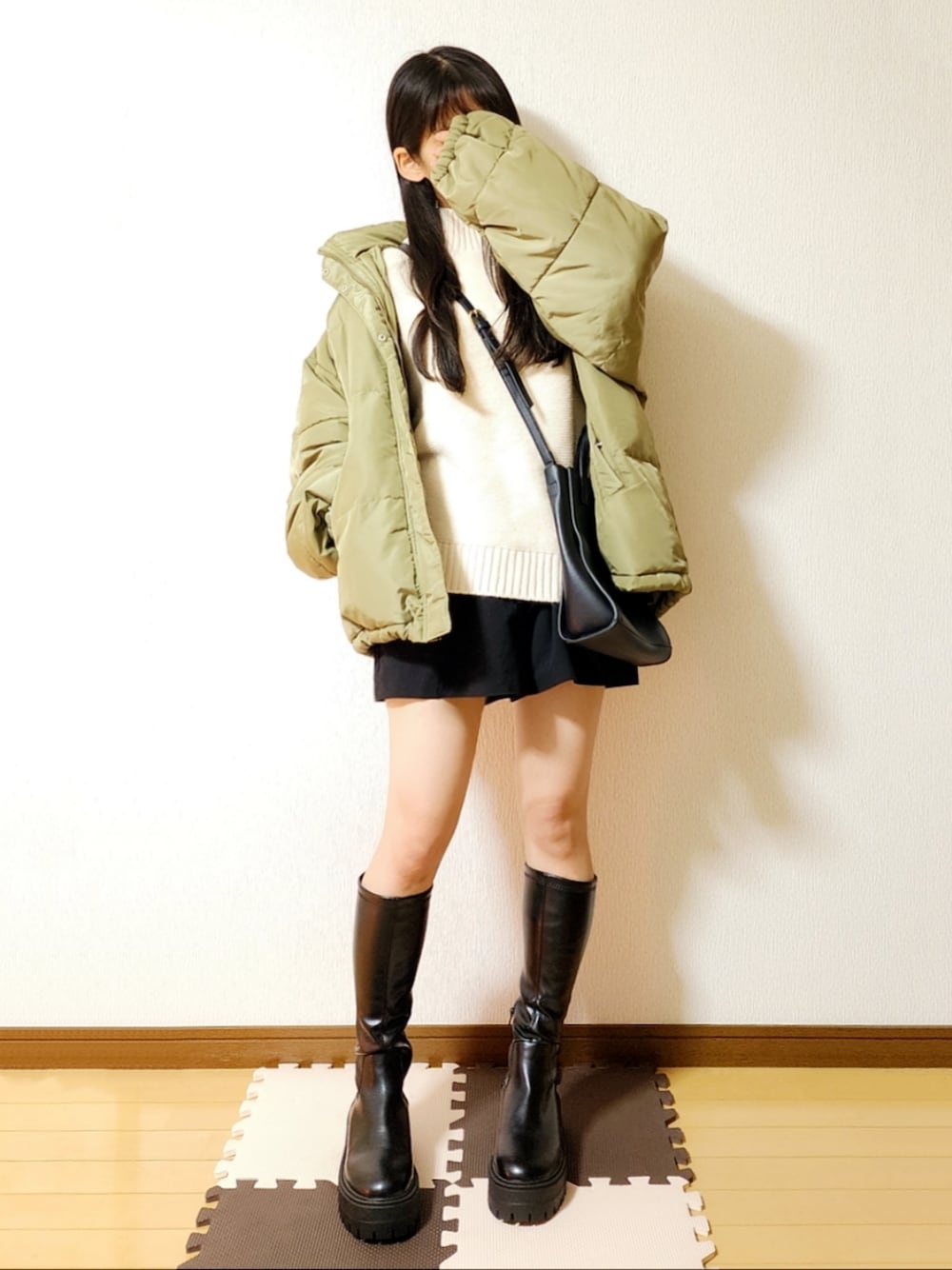 グリーン系のダウンジャケット/コート、ホワイト系のニット/セーター、ブラック系のその他パンツを着用したレディースの冬コーディネートの1枚目の写真