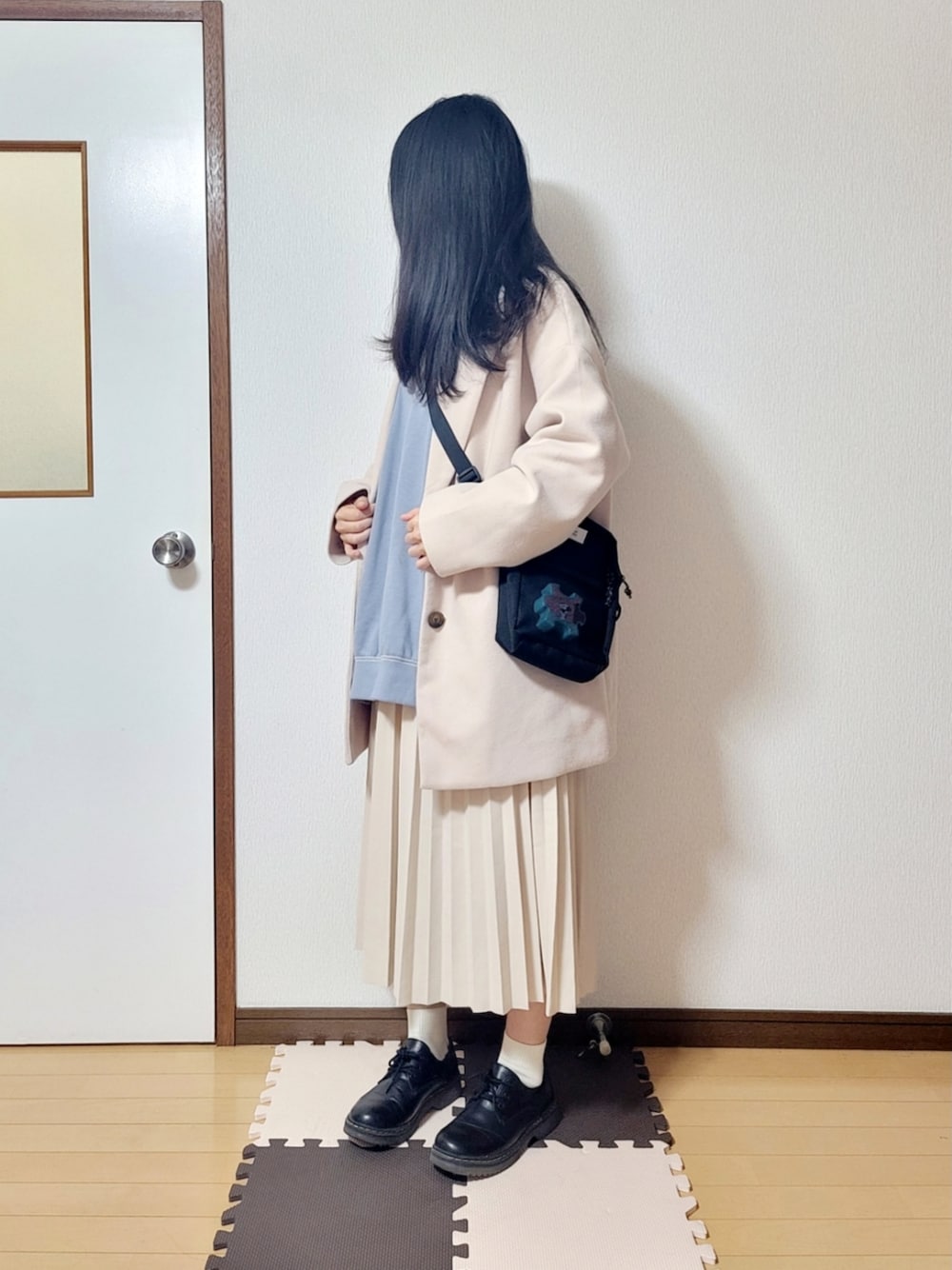 ベージュ系のダウンジャケット/コート、ブラック系のショルダーバッグ、ベージュ系のスカートを着用したレディースの冬コーディネートの1枚目の写真