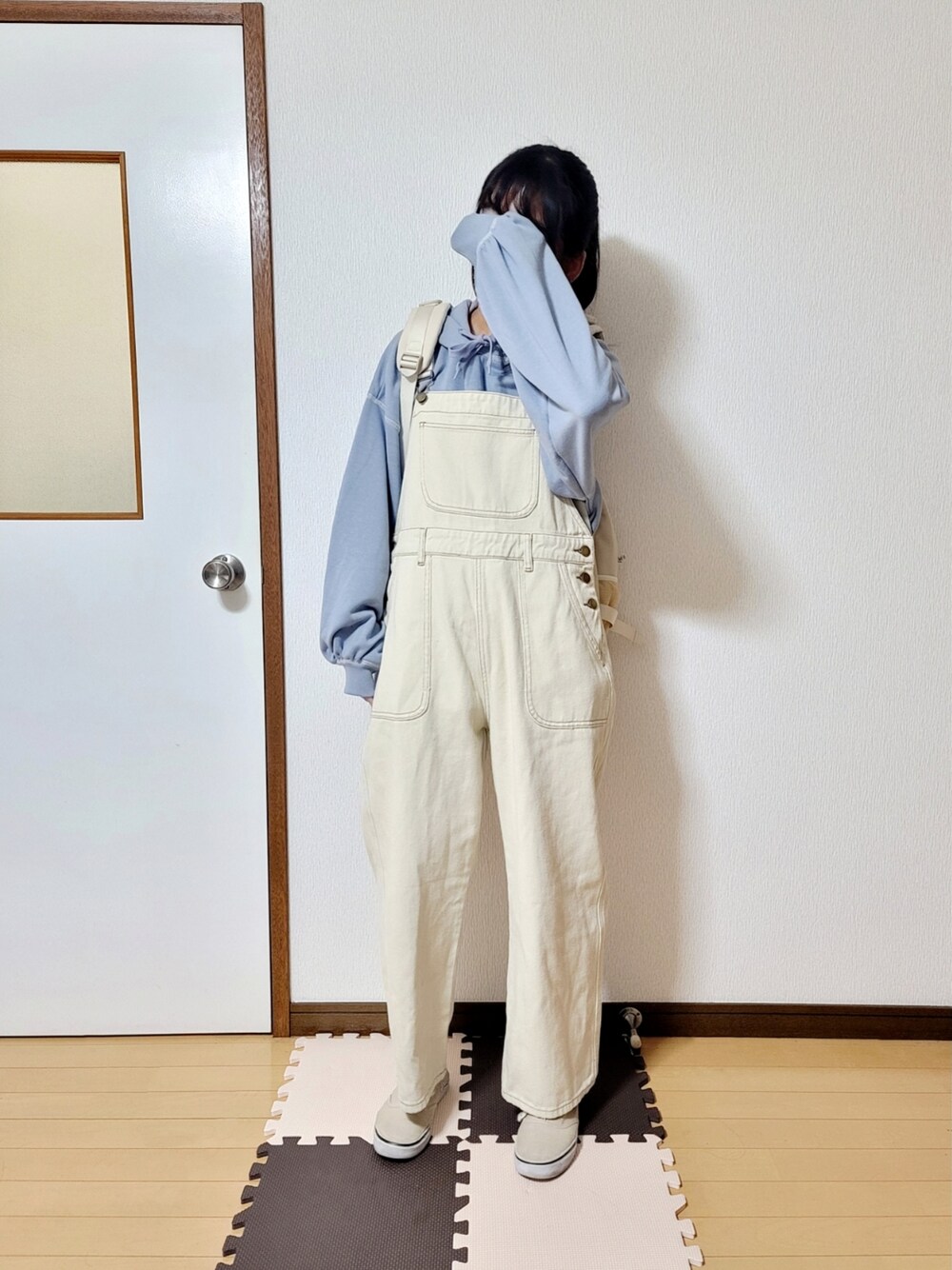 ベージュ系のダウンジャケット/コート、ベージュ系のバックパック/リュック、ベージュ系のサロペット/オーバーオールを着用したレディースの冬コーディネートの2枚目の写真