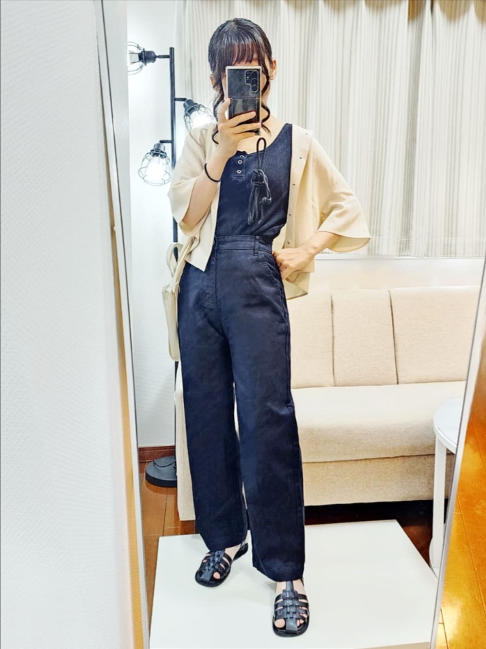 ブラック系のタンクトップ、ベージュ系のワンピース、ブラック系のデニムパンツを着用したレディースの夏コーディネートの1枚目の写真