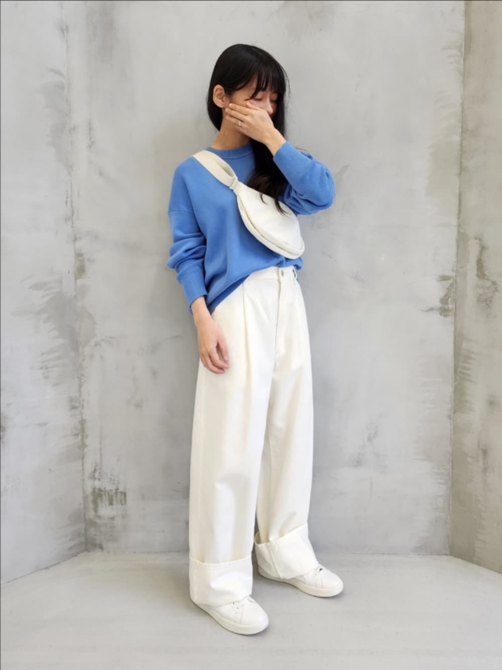 ホワイト系のスニーカー、ブルー系のニット/セーター、ホワイト系のデニムパンツを着用したレディースの冬コーディネートの1枚目の写真