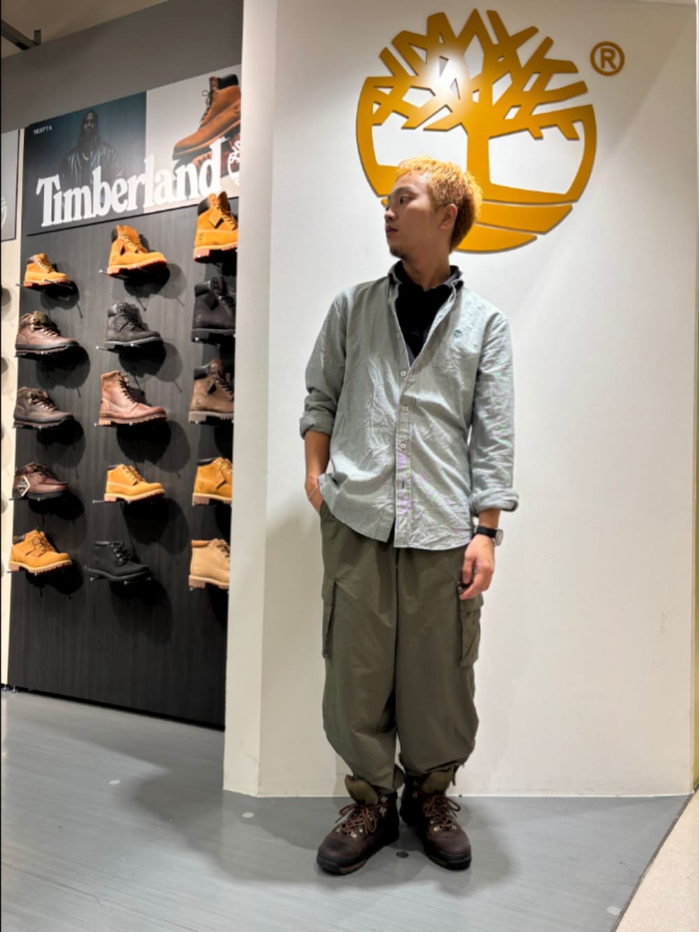 グリーン系のシャツ/ブラウス、ブラック系のポロシャツ、ブラウン系のブーツを着用したメンズの秋コーディネートの1枚目の写真