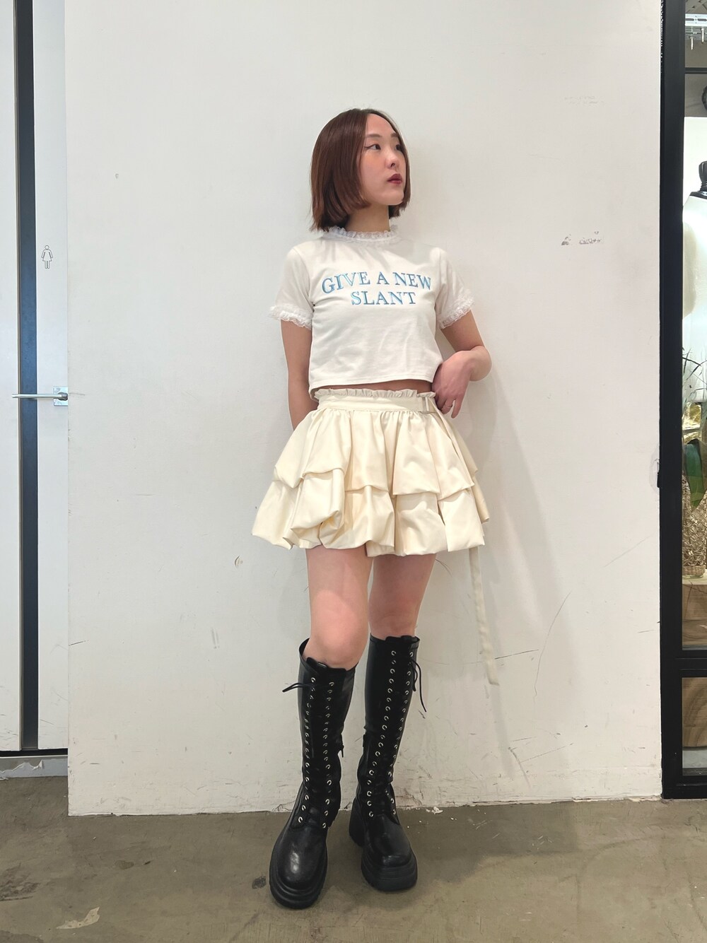 ホワイト系のTシャツ/カットソー、ホワイト系のスカート、ブラック系のブーツを着用したレディースの春コーディネートの1枚目の写真