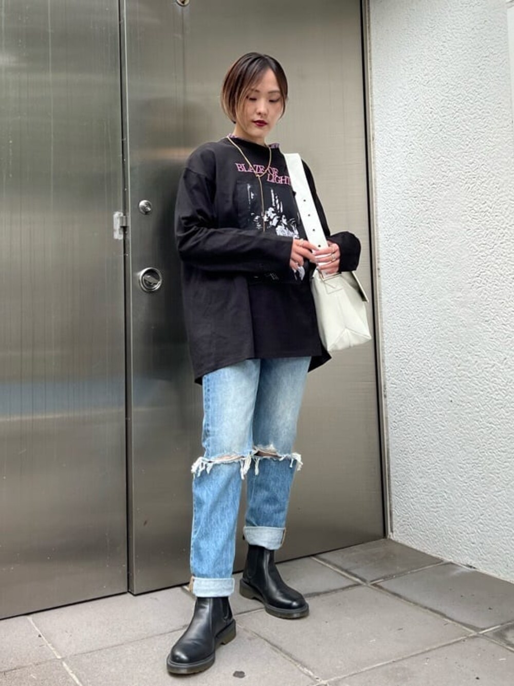 ブルー系のデニムパンツ、ホワイト系のハンドバッグ、パープル系のTシャツ/カットソーを着用したレディースの夏コーディネートの1枚目の写真