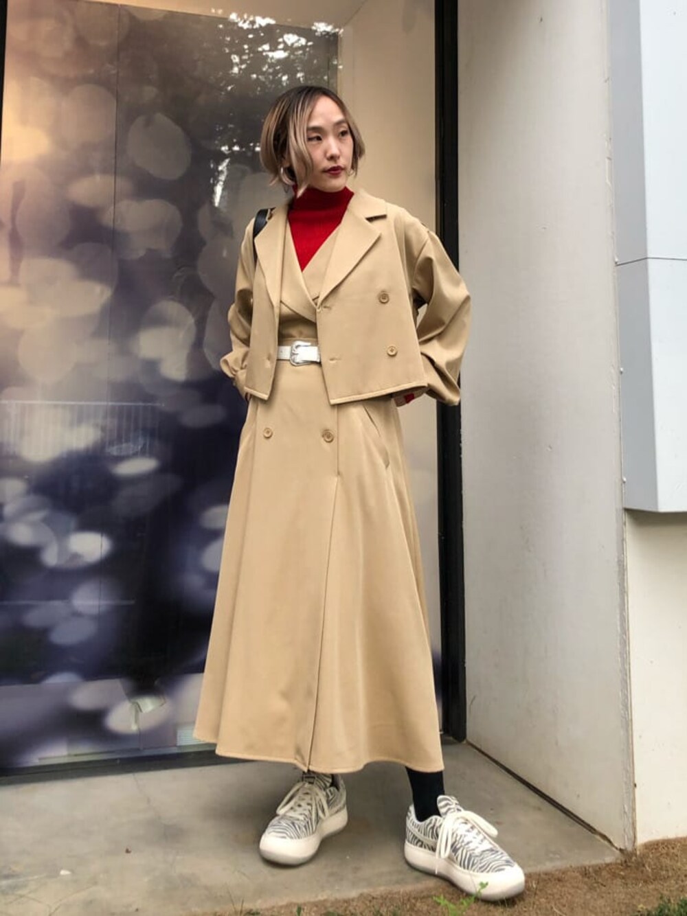 レッド系のニット/セーター、ホワイト系のスニーカー、ブラック系のショルダーバッグを着用したレディースの秋コーディネートの1枚目の写真