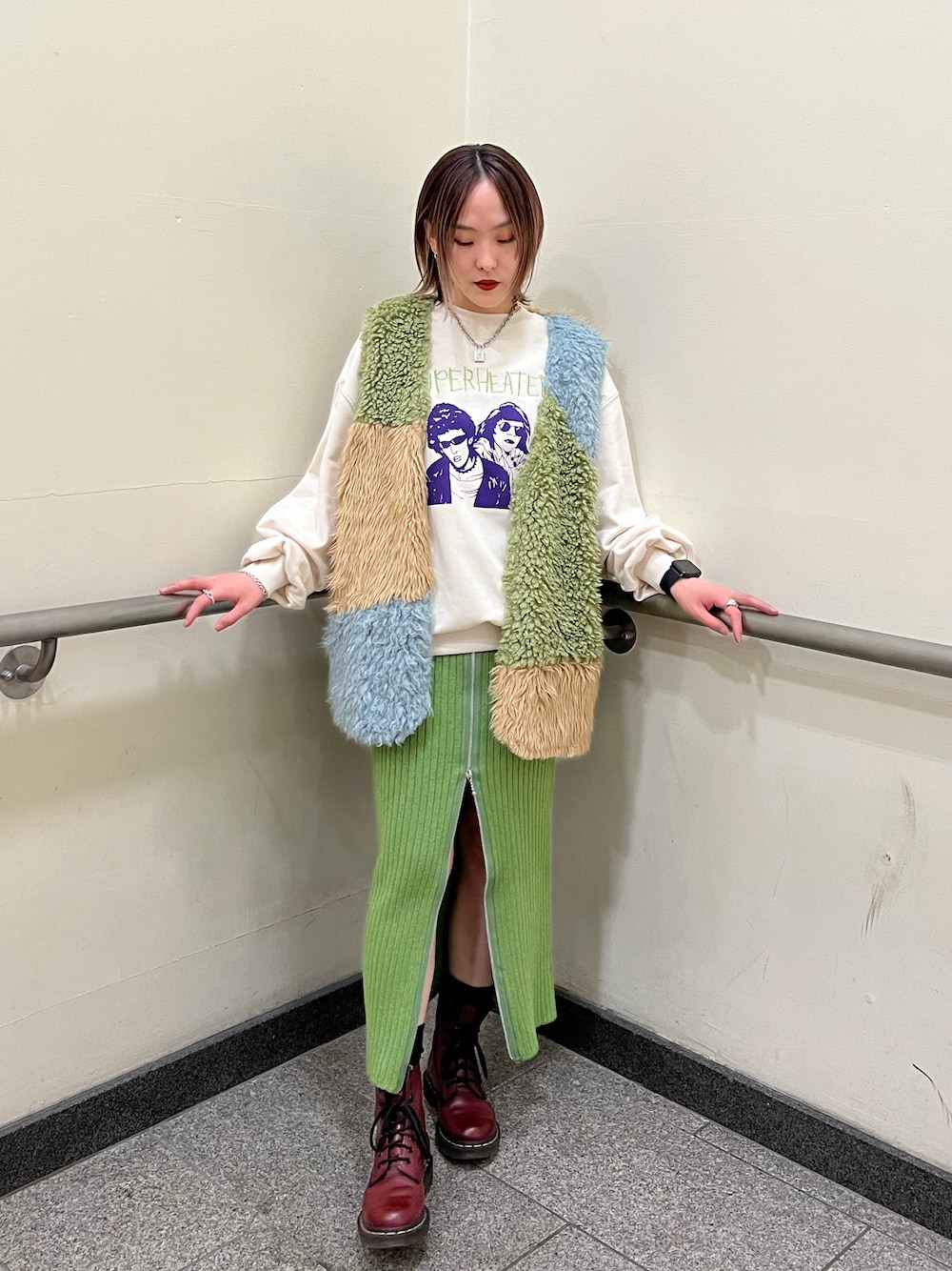 その他のベスト、ホワイト系のニット/セーター、グリーン系のスカートを着用したレディースの冬コーディネートの1枚目の写真