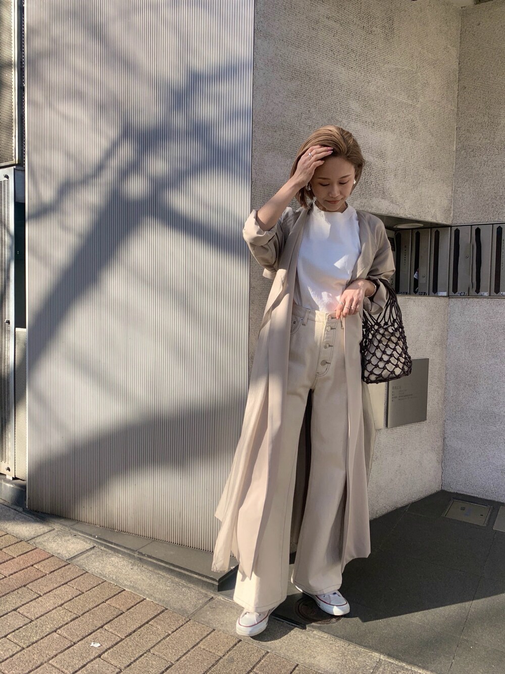 ホワイト系のその他パンツ、ベージュ系のその他アウター、ブラウン系のハンドバッグを着用したレディースの春コーディネートの1枚目の写真
