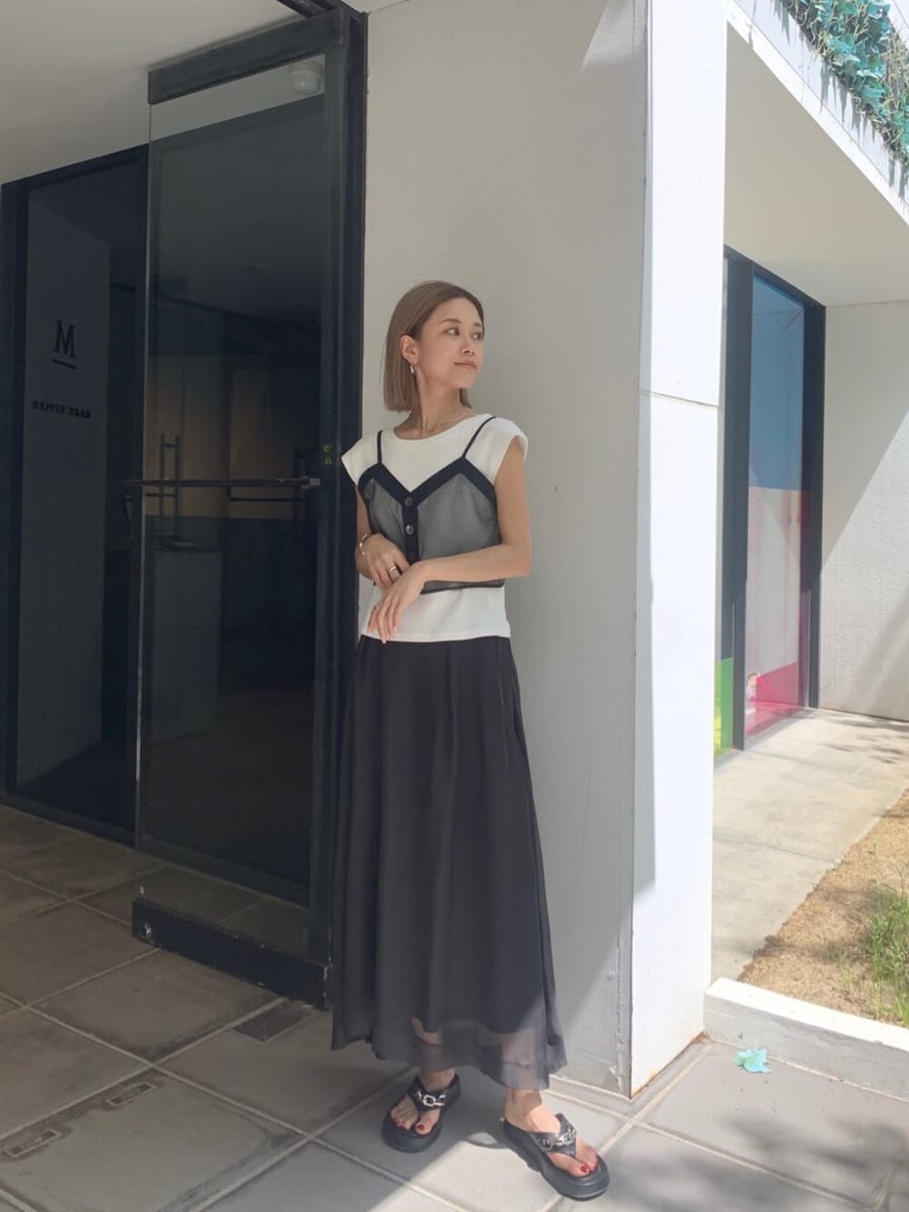 ブラック系のスカート、ブラック系のサンダル、ブラック系のTシャツ/カットソーを着用したレディースの夏コーディネートの1枚目の写真