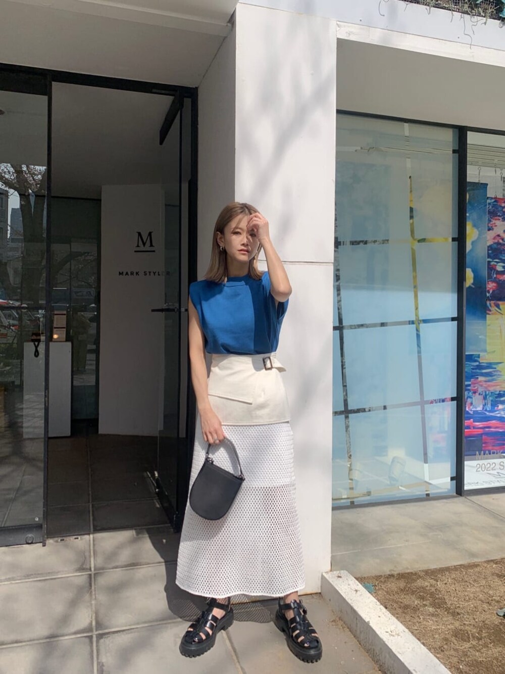 ホワイト系のスカート、ブラック系のサンダル、ブルー系のタンクトップを着用したレディースの春コーディネートの1枚目の写真