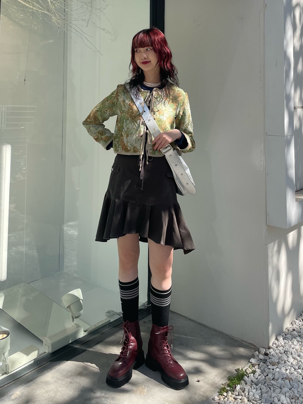 シルバー系のショルダーバッグ、ブラック系のスカート、レッド系のブーツを着用したレディースの冬コーディネートの1枚目の写真