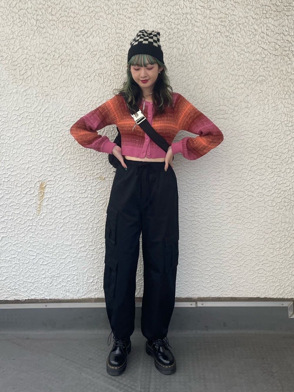 ブラック系のカーゴパンツ、ブラック系のハンドバッグ、ピンク系のカーディガン/ボレロを着用したレディースの秋コーディネートの1枚目の写真