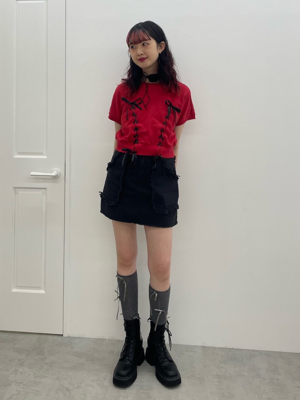 レッド系のTシャツ/カットソー、ブラック系のスカート、ブラック系のブーツを着用したレディースの夏コーディネートの1枚目の写真
