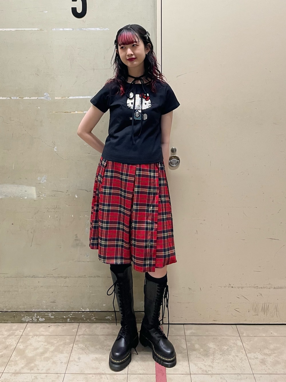 ブラック系のTシャツ/カットソー、レッド系のスカート、ブラック系のブーツを着用したレディースの春コーディネートの1枚目の写真