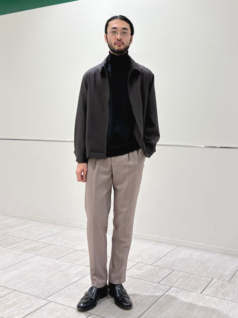 ベージュ系のスラックス、グレー系のニット/セーター、グレー系のブルゾンを着用したメンズの冬コーディネートの1枚目の写真