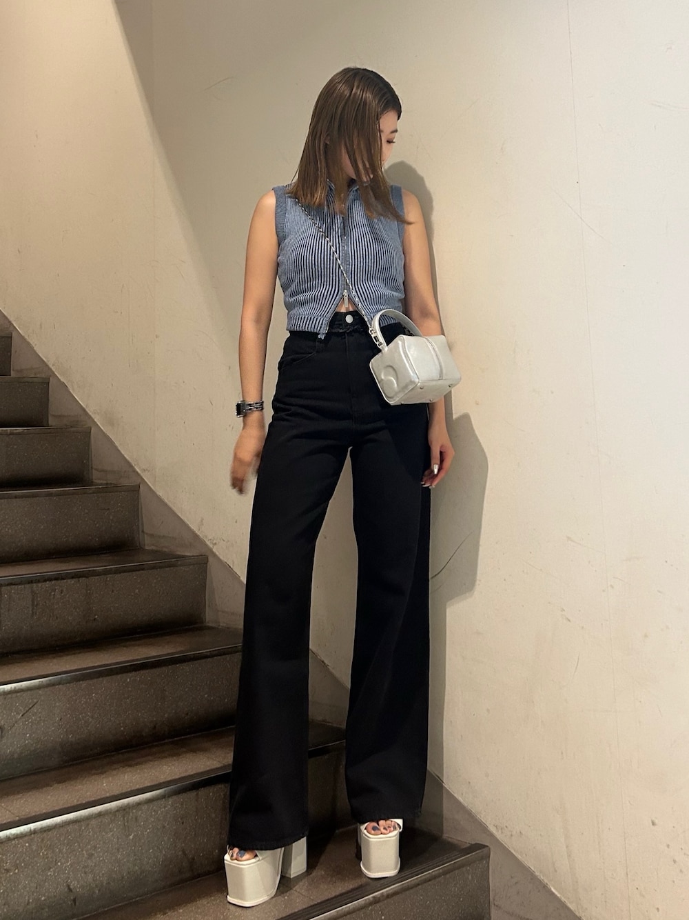 ブルー系のニット/セーター、ブラック系のデニムパンツ、ホワイト系のサンダルを着用したレディースの夏コーディネートの1枚目の写真