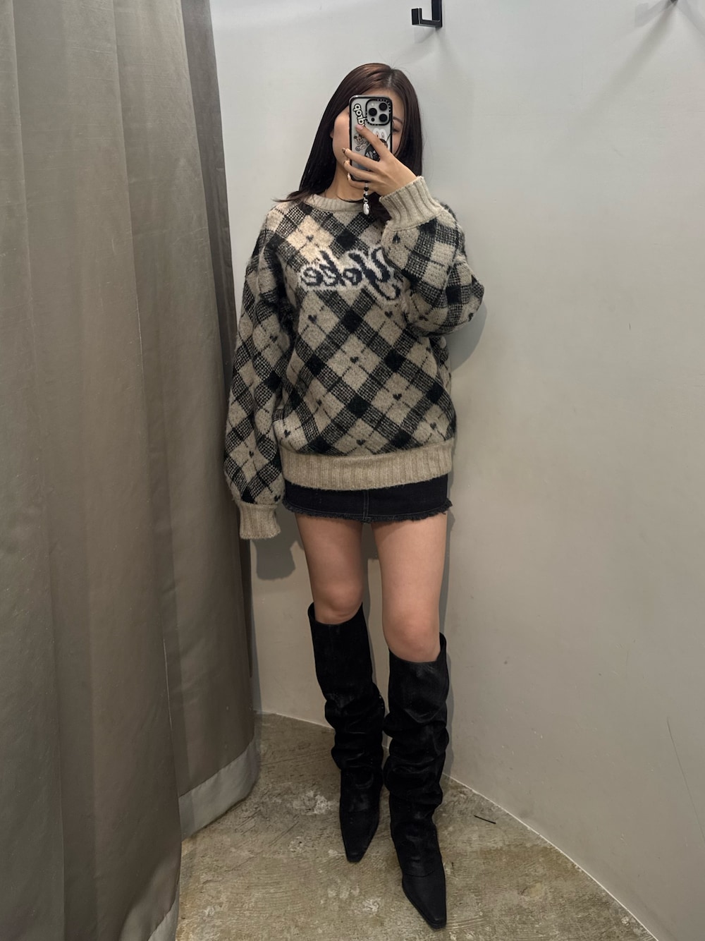 ホワイト系のニット/セーター、ブラック系のスカート、ブラック系のブーツを着用したレディースの冬コーディネートの1枚目の写真