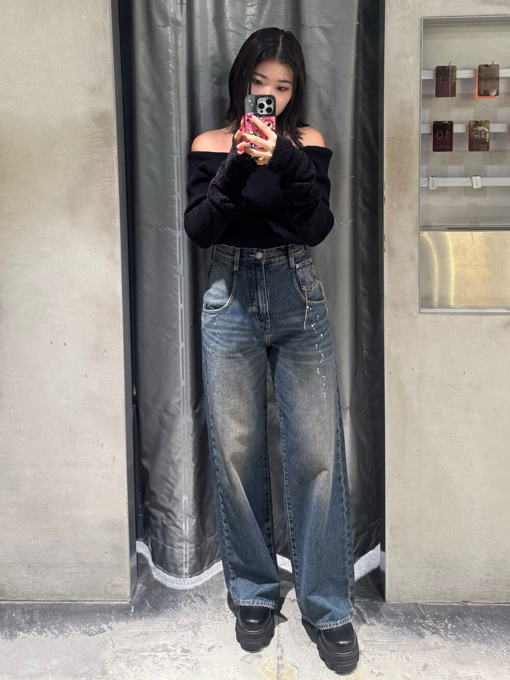 ブラック系のニット/セーター、ブルー系のデニムパンツ、ブラック系のブーツを着用したレディースの秋コーディネートの1枚目の写真