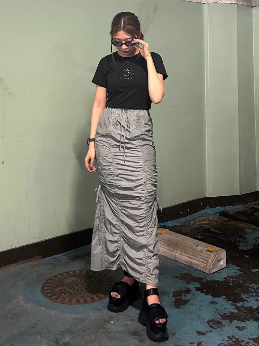 ブラック系のTシャツ/カットソー、グレー系のスカート、ブラック系のサンダルを着用したレディースの夏コーディネートの1枚目の写真