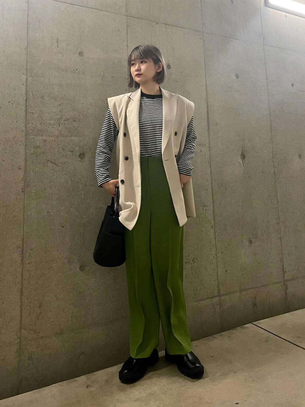 ベージュ系のベスト、グリーン系のその他パンツ、ブラック系のトートバッグを着用したレディースの冬コーディネートの1枚目の写真