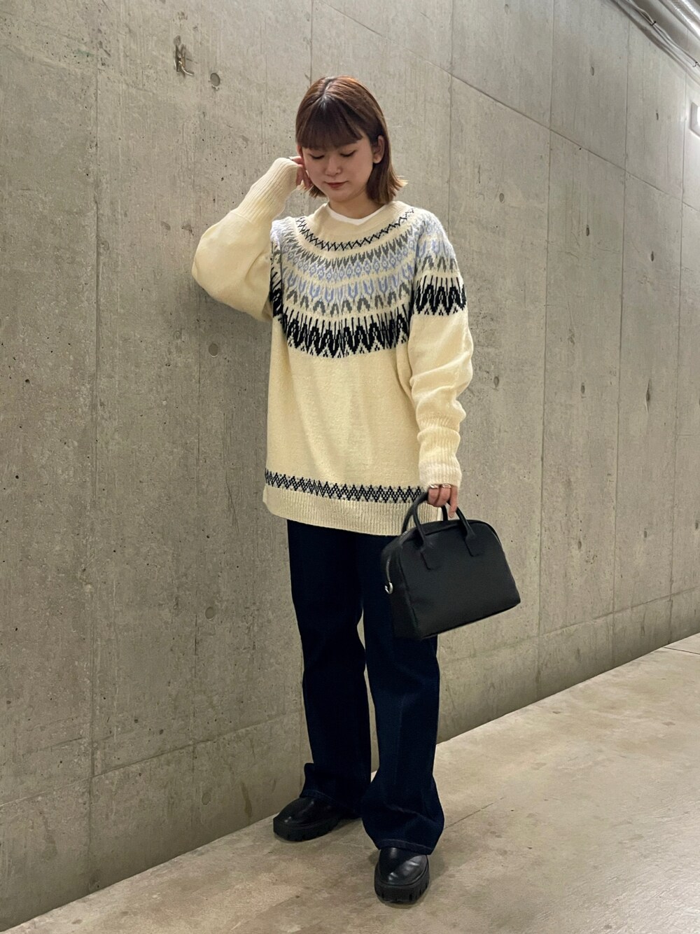 ブラック系のボストンバッグ、ブルー系のデニムパンツ、ホワイト系のニット/セーターを着用したレディースの冬コーディネートの1枚目の写真