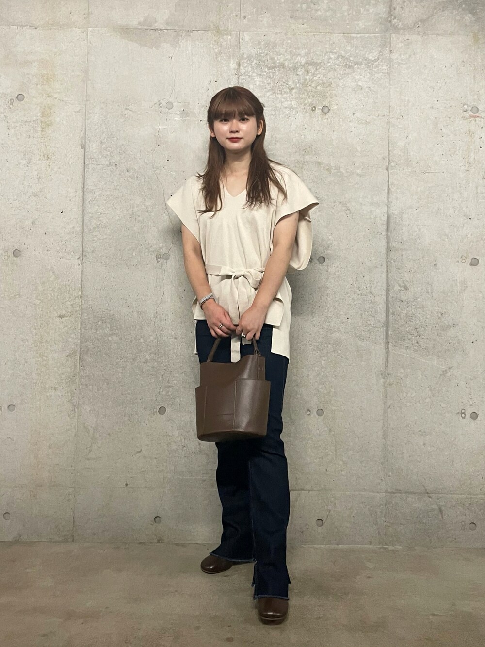 ホワイト系のベスト、ブルー系のデニムパンツ、ブラウン系のブーツを着用したレディースの秋コーディネートの1枚目の写真