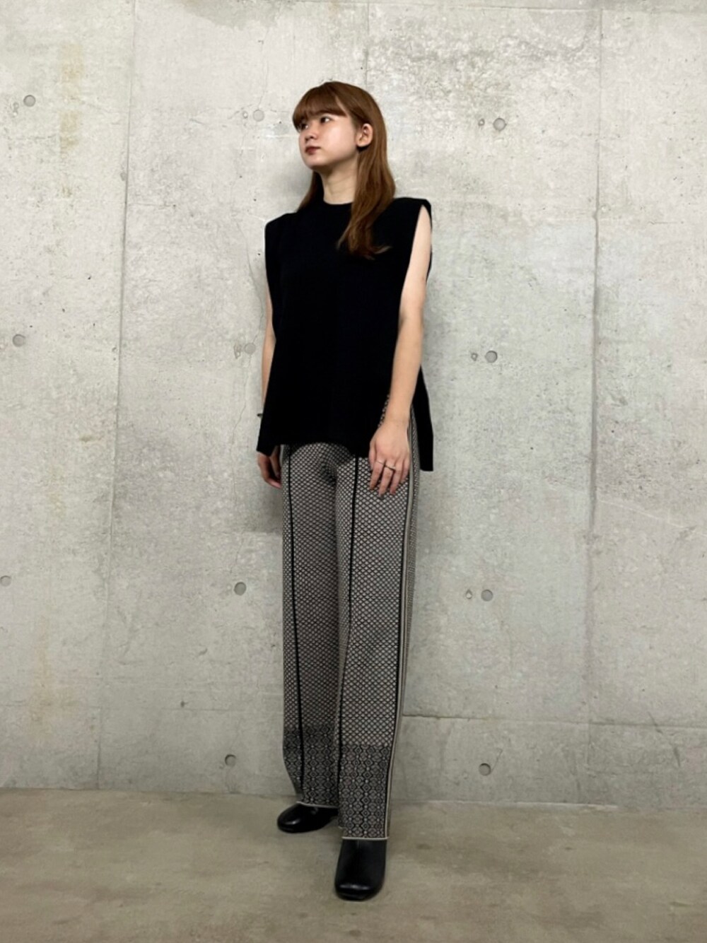 ブラック系のニット/セーター、ブラック系のその他パンツ、ブラウン系のブーツを着用したレディースの秋コーディネートの1枚目の写真