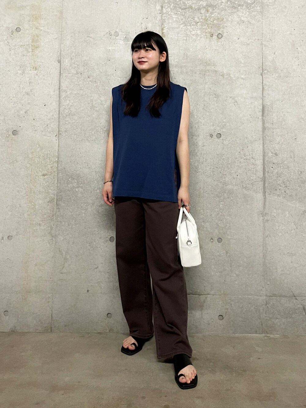 ホワイト系のボストンバッグ、ブルー系のニット/セーター、ブラウン系のデニムパンツを着用したレディースの夏コーディネートの1枚目の写真