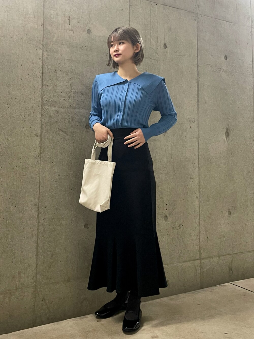 ホワイト系のトートバッグ、ブラック系のスカート、ブルー系のカーディガン/ボレロを着用したレディースの春コーディネートの1枚目の写真