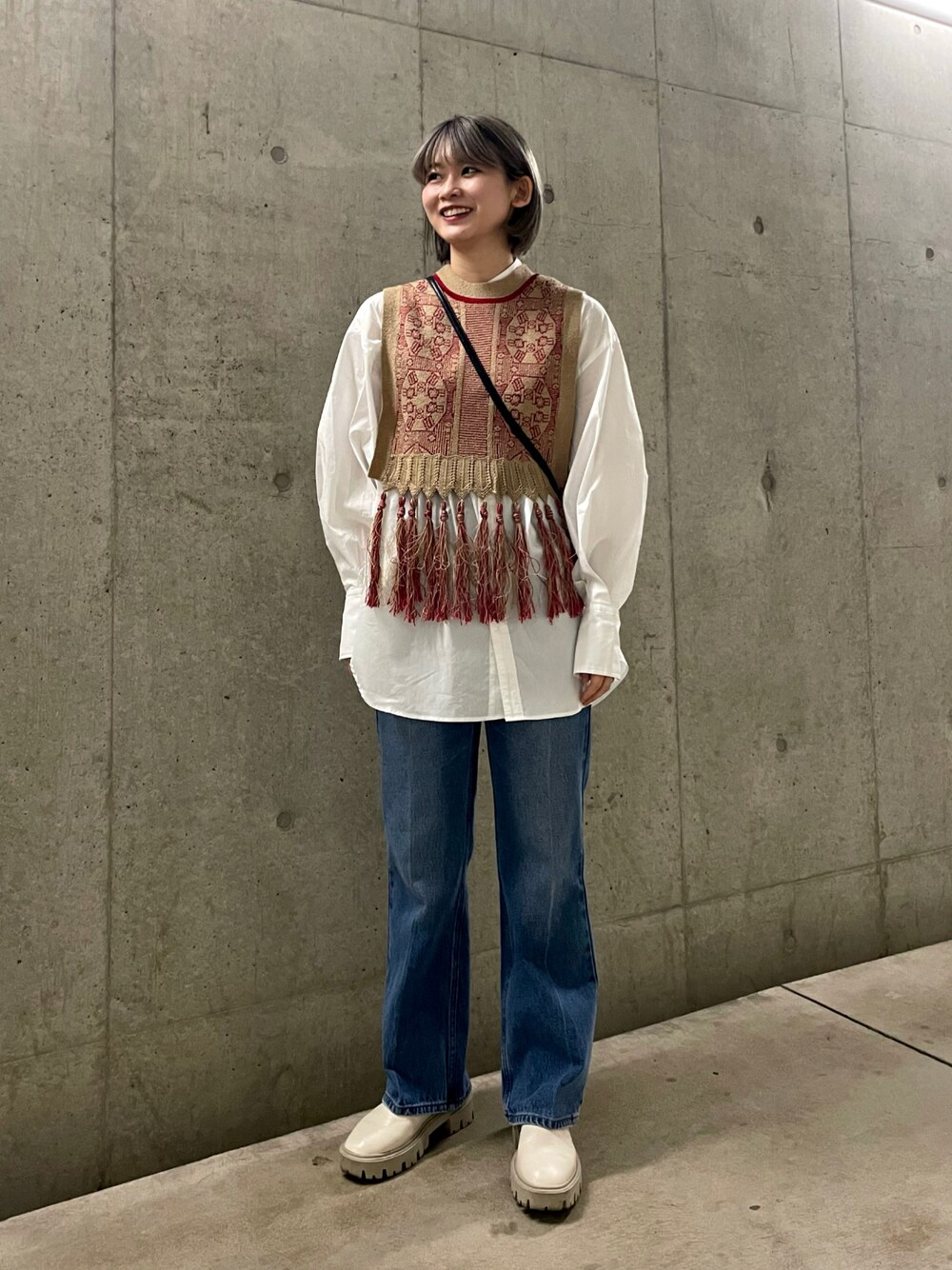 ブラック系のショルダーバッグ、レッド系のベスト、ホワイト系のシャツ/ブラウスを着用したレディースの春コーディネートの1枚目の写真