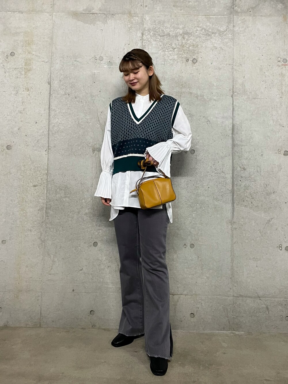 イエロー系のショルダーバッグ、グリーン系のニット/セーター、グレー系のその他パンツを着用したレディースの秋コーディネートの1枚目の写真