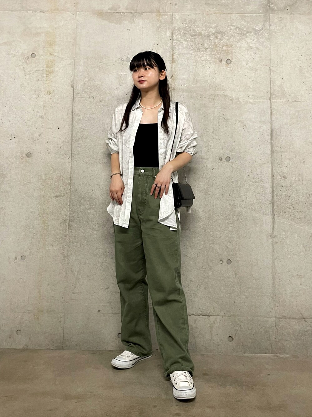 ブラック系のショルダーバッグ、ホワイト系のシャツ/ブラウス、グリーン系のデニムパンツを着用したレディースの夏コーディネートの1枚目の写真