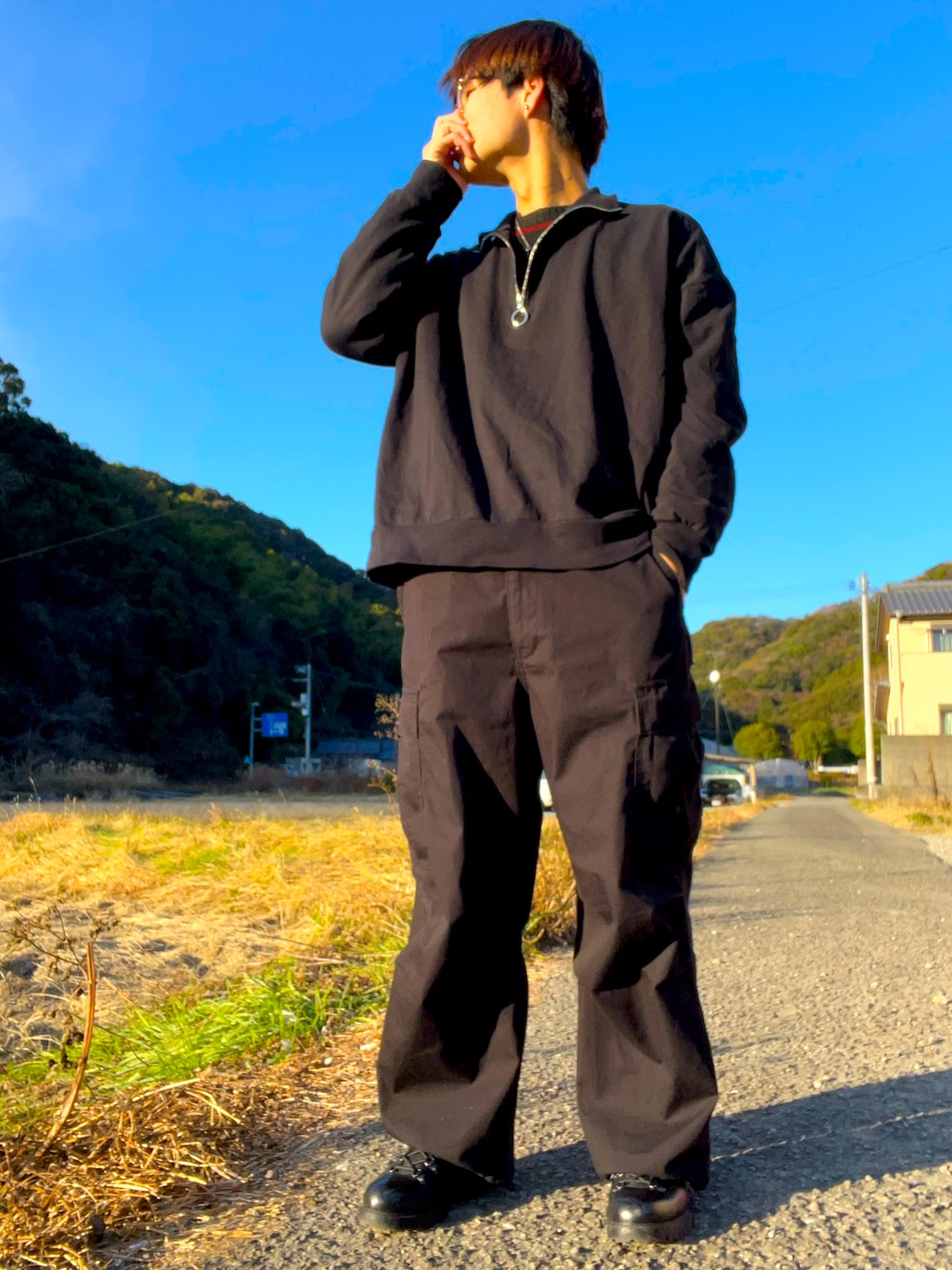 レッド系のニット/セーター、ブラック系のTシャツ/カットソー、ブラック系のカーゴパンツを着用したメンズの冬コーディネートの1枚目の写真