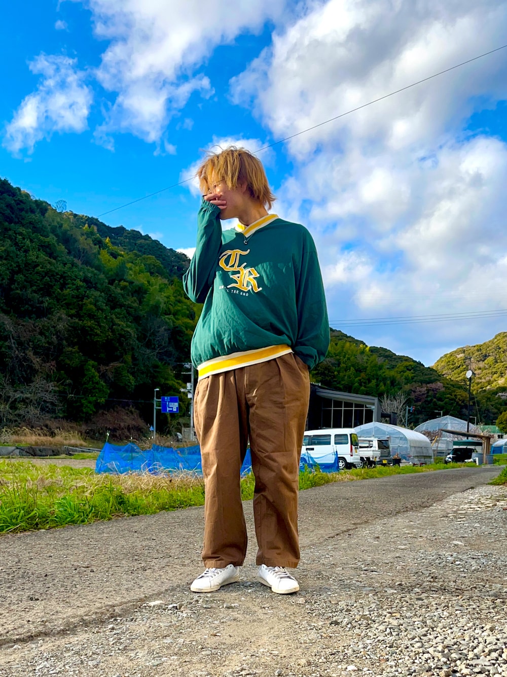 グリーン系のTシャツ/カットソー、ブラウン系のスラックス、ホワイト系のスニーカーを着用したメンズの春コーディネートの1枚目の写真