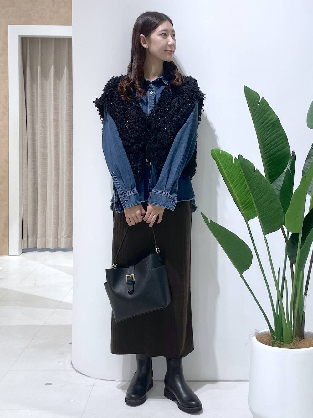 ブラウン系のスカート、ブラック系のブーツ、ブラック系のショルダーバッグを着用したレディースの秋コーディネートの1枚目の写真