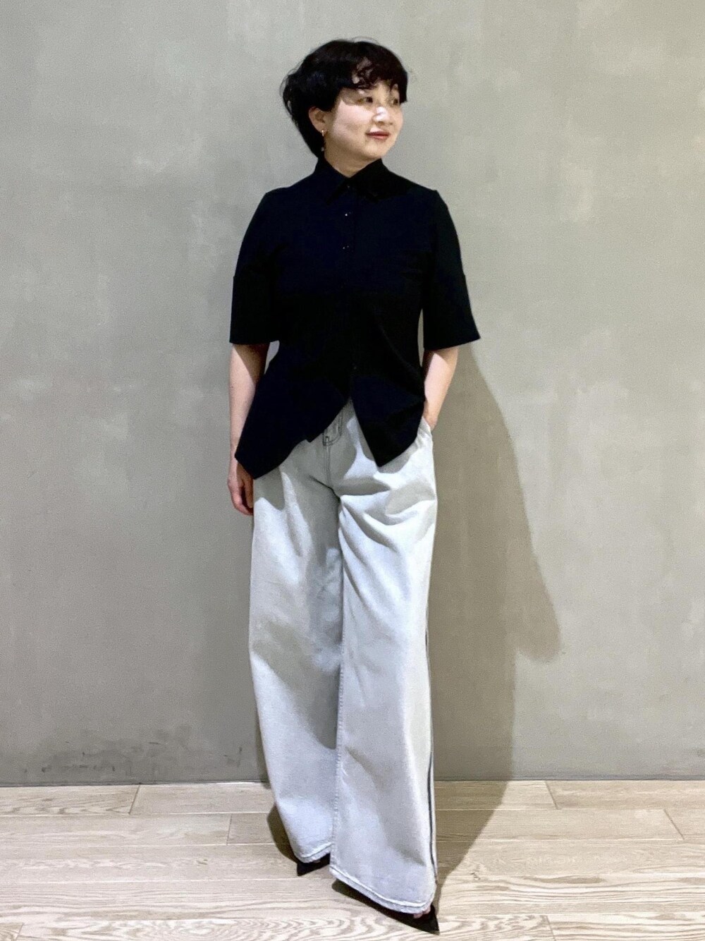 ブルー系のデニムパンツ、ブラック系のシャツ/ブラウス、ブラック系のサンダルを着用したレディースの春コーディネートの1枚目の写真