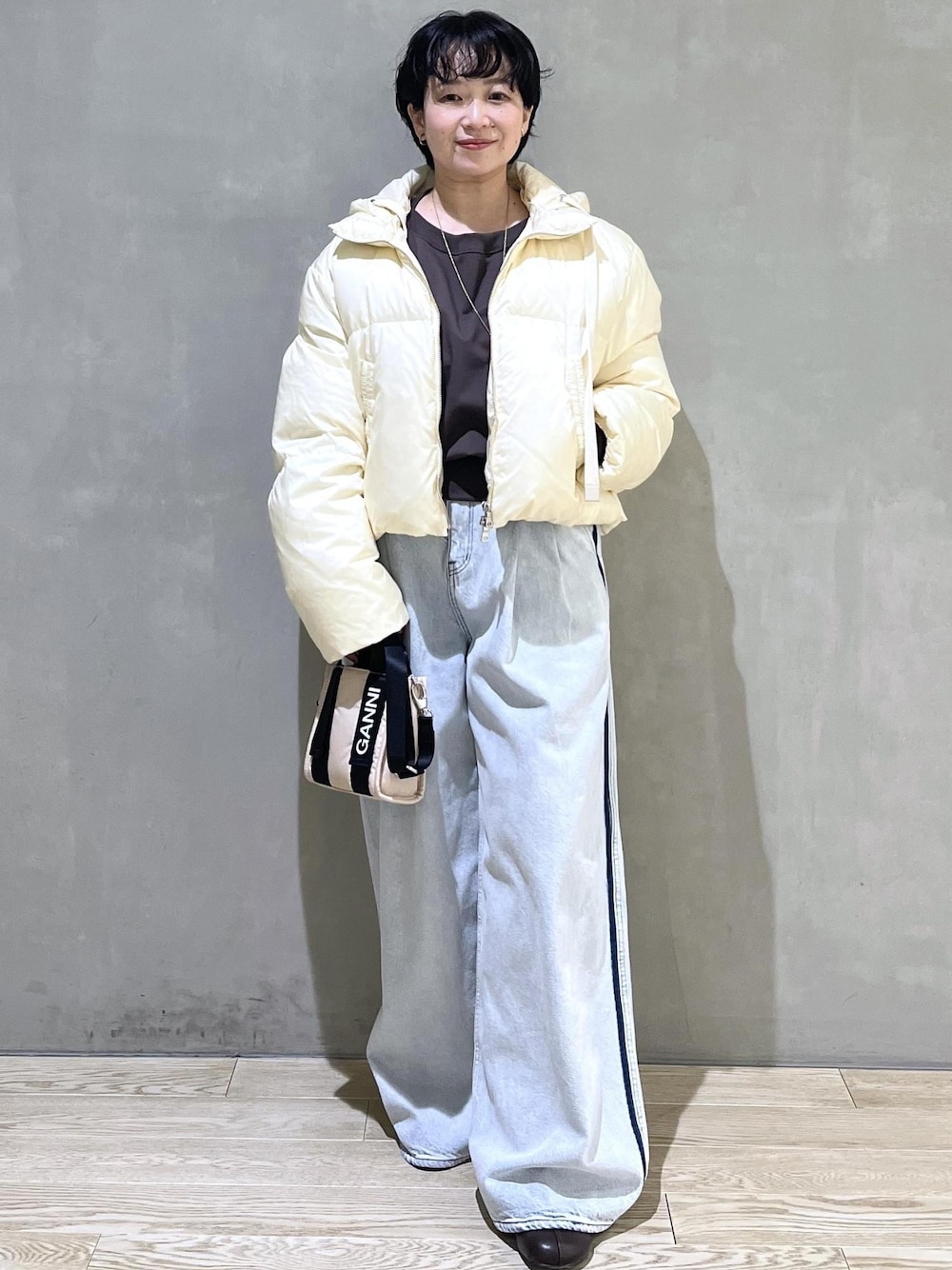 ベージュ系のトートバッグ、ブルー系のデニムパンツ、ブラウン系のスウェットを着用したレディースの秋コーディネートの1枚目の写真