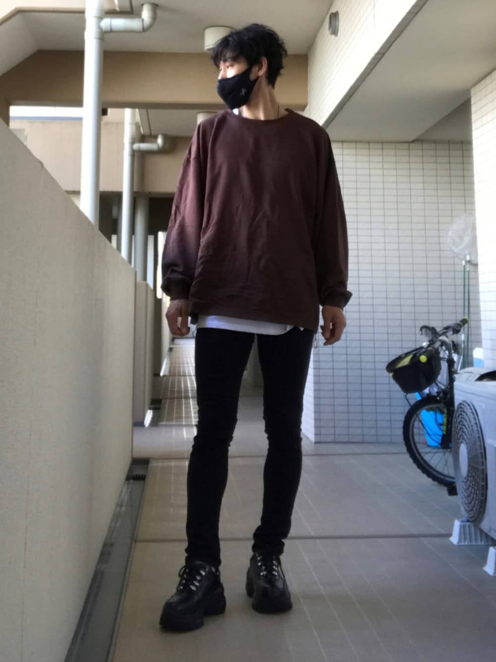 ブラウン系のスウェット、ホワイト系のタンクトップ、ブラック系のデニムパンツを着用したメンズの秋コーディネートの1枚目の写真