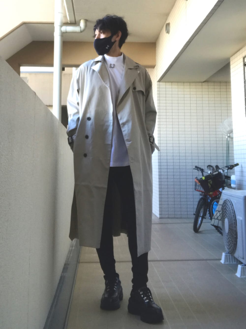 ホワイト系のTシャツ/カットソー、ベージュ系のトレンチコート、ブラック系のデニムパンツを着用したメンズの秋コーディネートの1枚目の写真